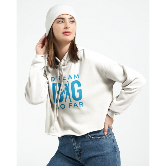 Woman wearing white cropped hoodie with "Dream BIG Go Far" motivational text in blue, paired with a white beanie and blue jeans