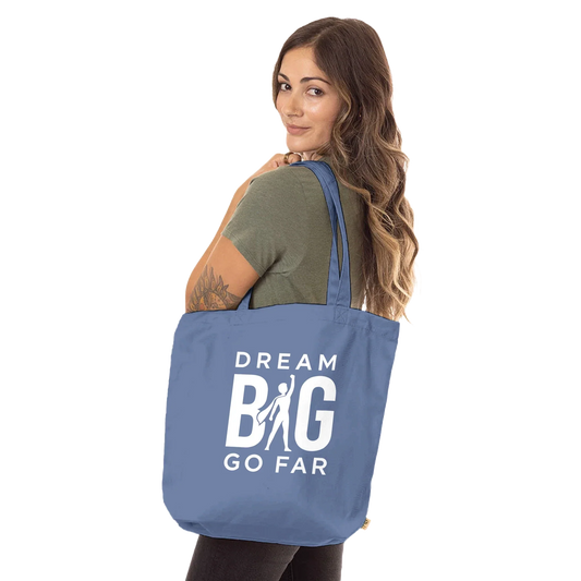 Woman carrying a blue Dream BIG Tote Bag with motivational text and long handles made from organic cotton