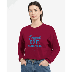 Woman wearing burgundy cropped sweatshirt with "Dream it. DO IT. ACHIEVE IT." motivational text in blue