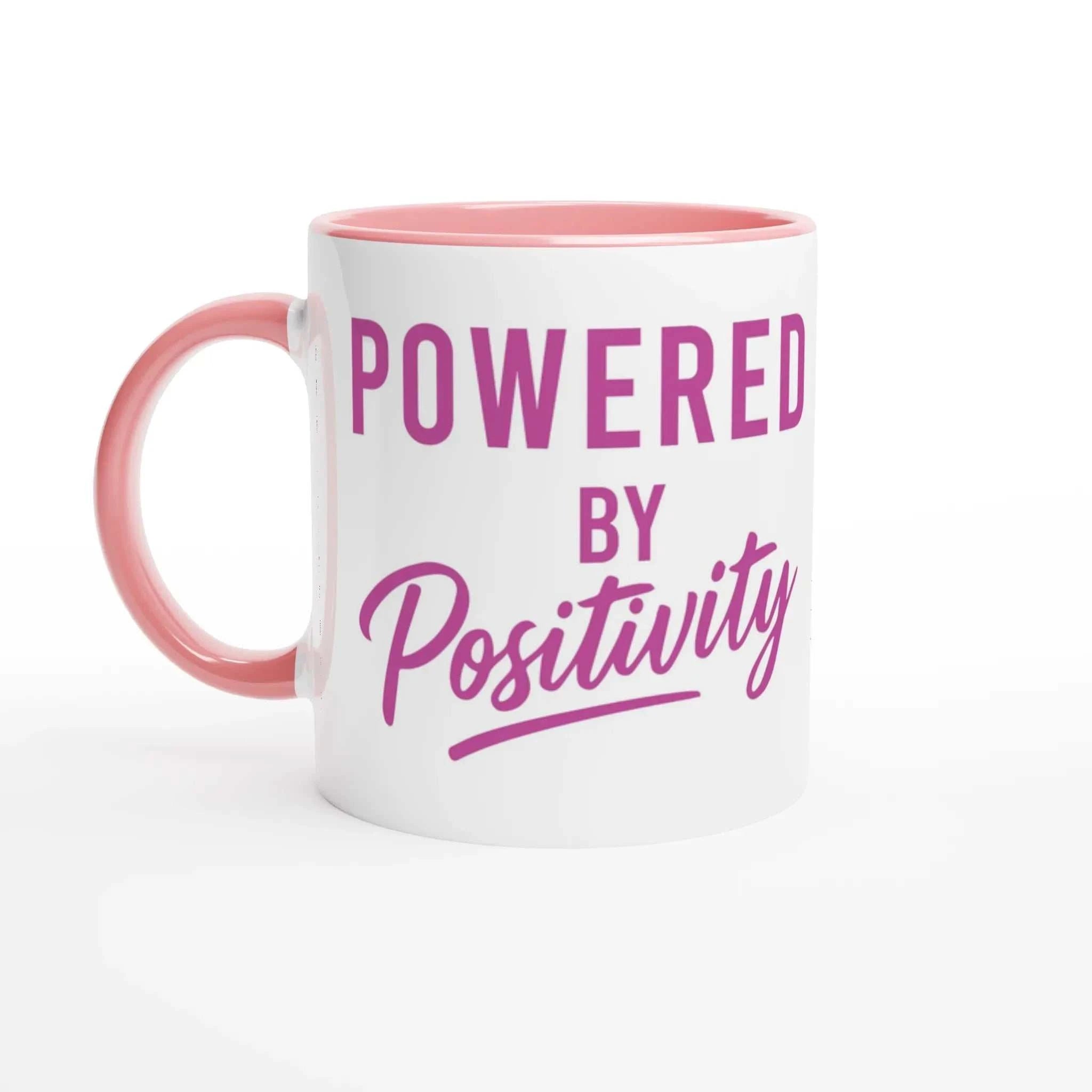 11oz ceramic mug with pink handle and interior, featuring "Powered by Positivity" motivational text in purple on white background
