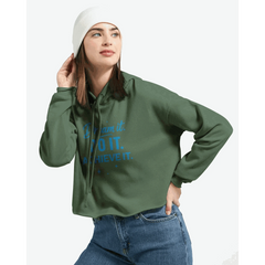 Woman wearing green cropped hoodie with "Dream It. DO IT. Achieve It." motivational text, paired with white beanie and jeans