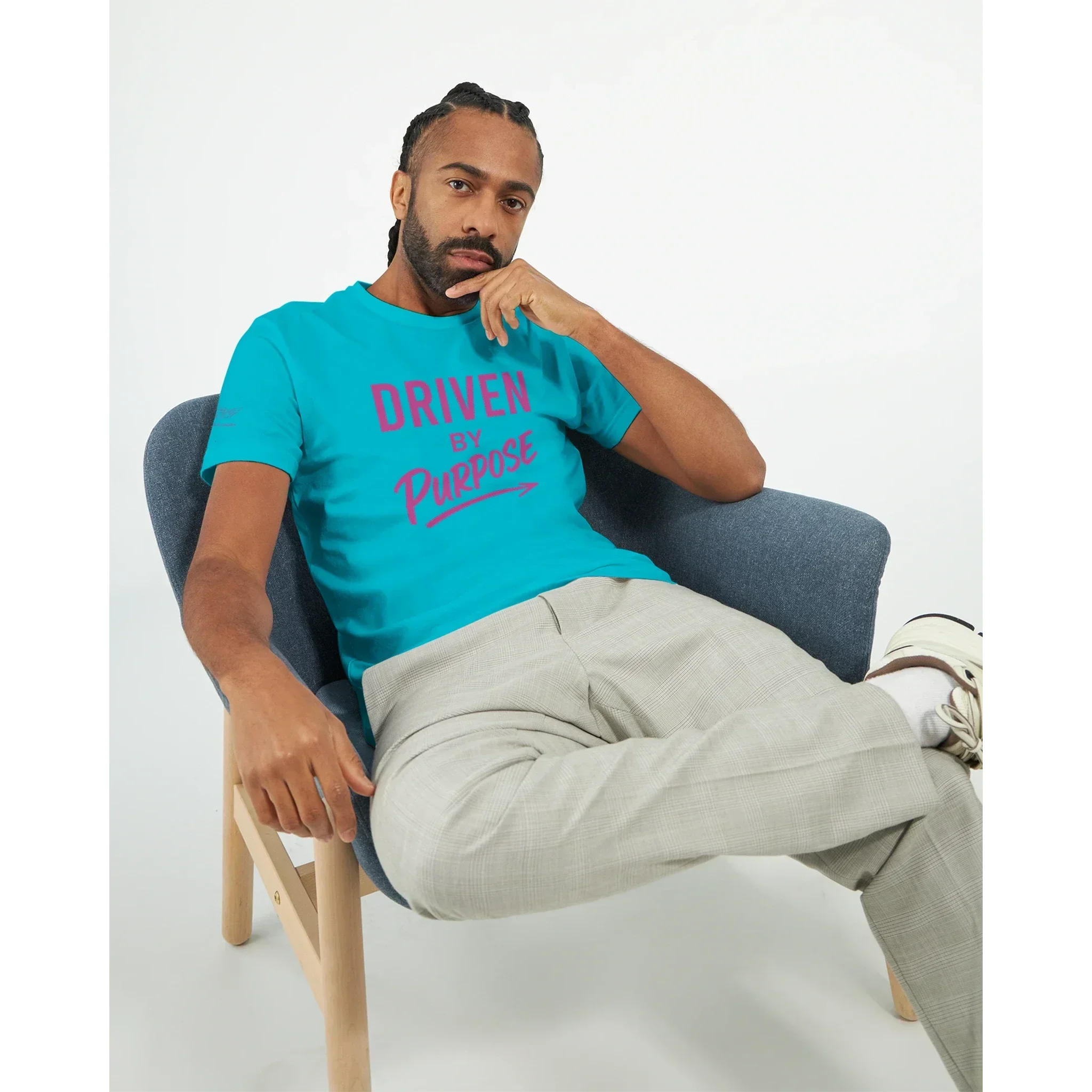 Man wearing a bright blue fitted t-shirt with "Driven by Purpose" motivational text sitting in a modern chair